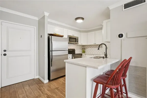 a kitchen with stainless steel appliances a refrigerator a sink a stove a table and chairs