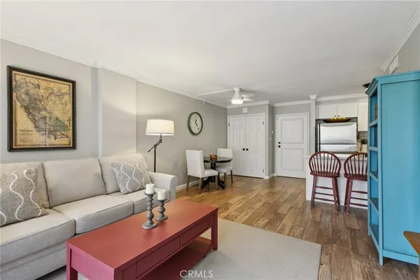 a living room with furniture kitchen view and a wooden floor