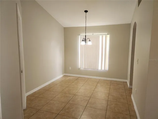 a view of an empty room with window and chandelier fan