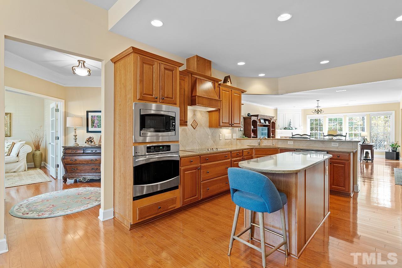 113 Beckingham Loop Cary, NC 27519 - Photo 14 of 46 a kitchen with stainless steel appliances granite countertop a kitchen island a stove a sink a dining table and chairs
