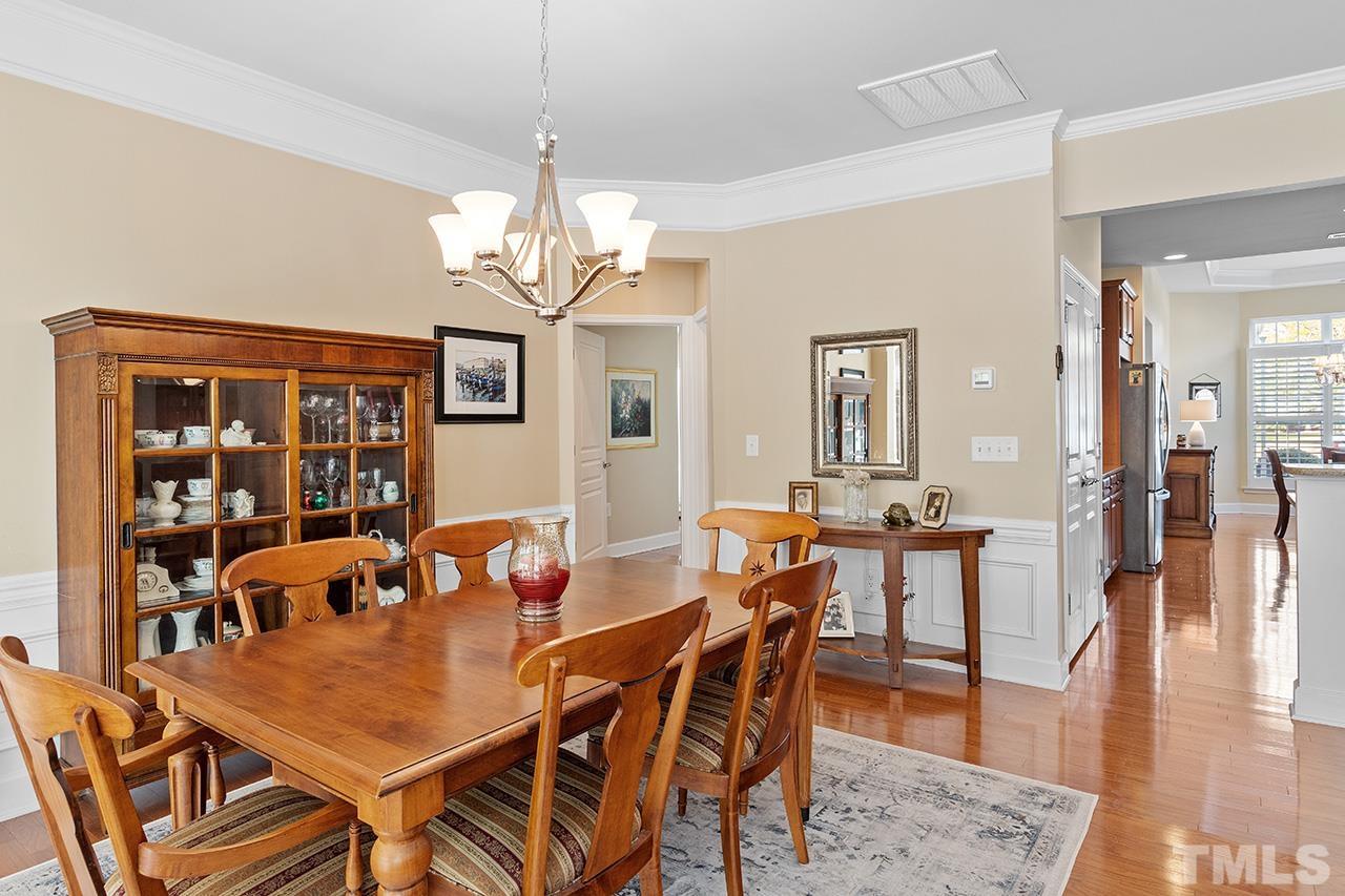 113 Beckingham Loop Cary, NC 27519 - Photo 22 of 46 a dining room with wooden floor a chandelier a wooden table and chairs