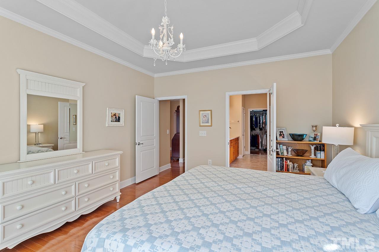 113 Beckingham Loop Cary, NC 27519 - Photo 27 of 46 a bedroom with a large bed and a chandelier