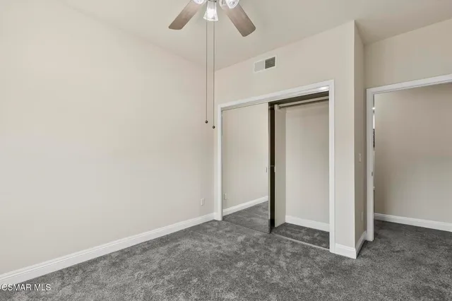 an empty room with chandelier fan and windows