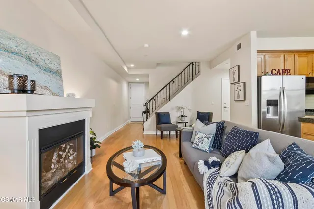 a kitchen with stainless steel appliances granite countertop a stove a refrigerator a microwave a dining table and chairs with wooden floor