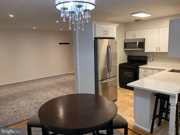 a kitchen with stainless steel appliances granite countertop a dining table chairs refrigerator and a sink