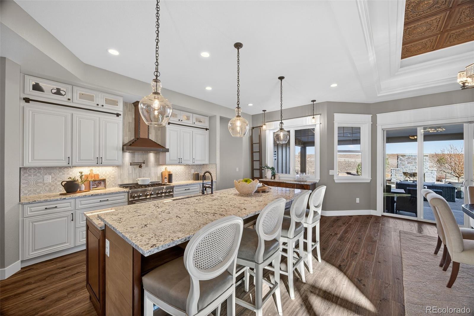 3444 Antelope Ridge Trail Parker, CO 80138 - Photo 12 of 50 a kitchen with granite countertop a table chairs stove and cabinets
