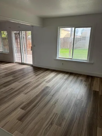 an empty room with wooden floor and windows