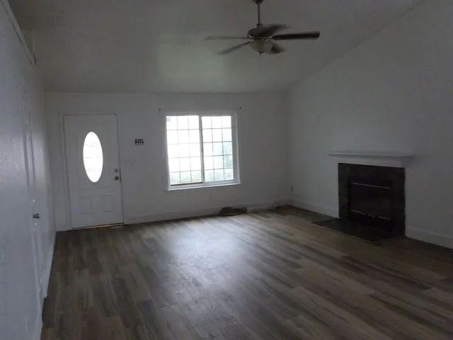 an empty room with wooden floor cabinet and windows