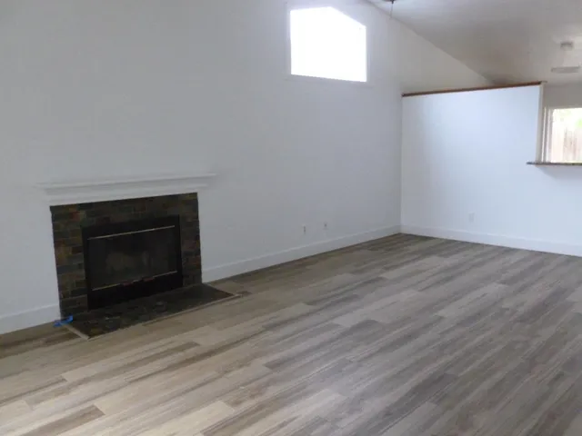 a view of empty room with wooden floor and fireplace