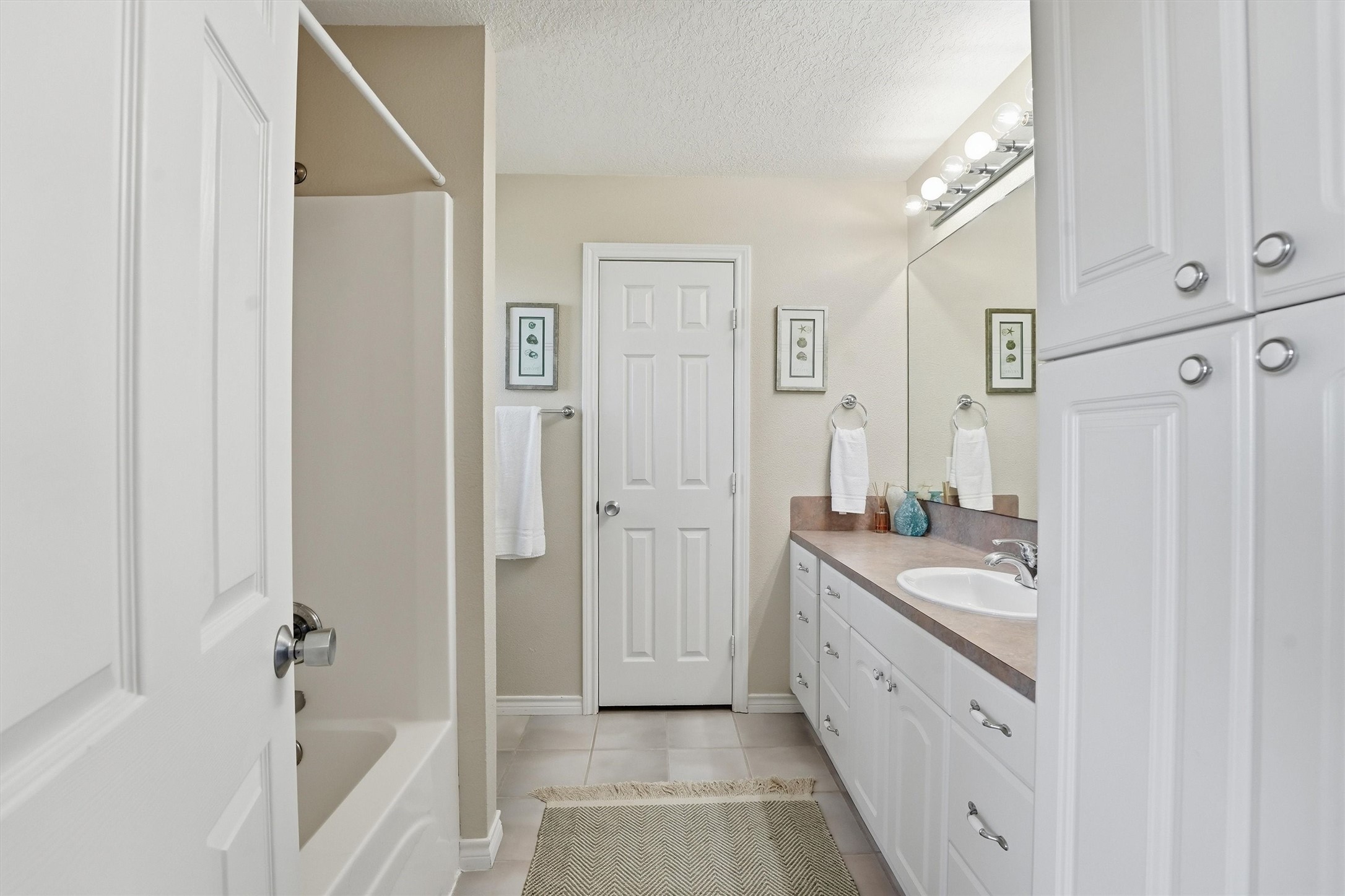 12902 John Reynolds Road Galveston, TX 77554 - Photo 14 of 22 a bathroom with a granite countertop sink a mirror a vanity and a bathtub
