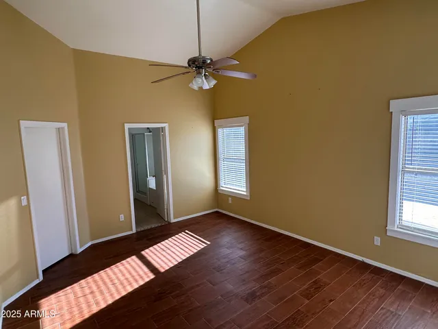 a view of an empty room with window and wooden floor