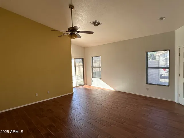 a view of empty room with wooden floor and fan