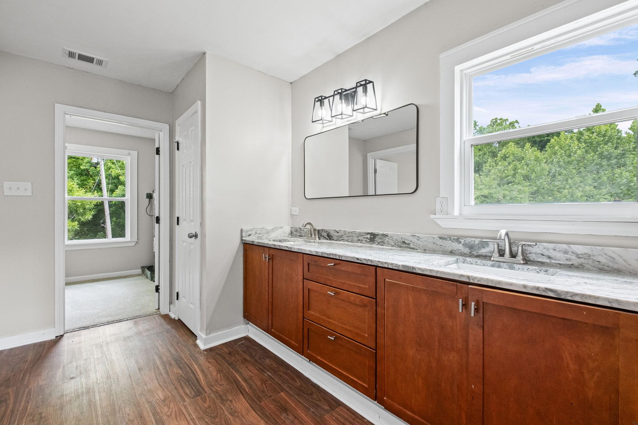5843 Stewart Road Lakeland, TN 38002 - Photo 20 of 26 Double vanity with stone countertop, integrated sinks, wood-finish cabinetry, and contemporary light fixture