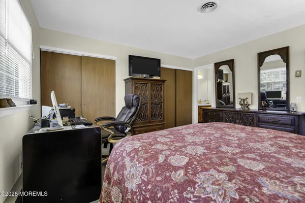 a bedroom with a bed and a large mirror on the dresser