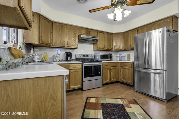 a kitchen with stainless steel appliances granite countertop a sink a stove a refrigerator cabinets and chairs