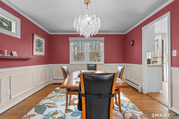 a dining room with wooden floor a chandelier a wooden table and chairs