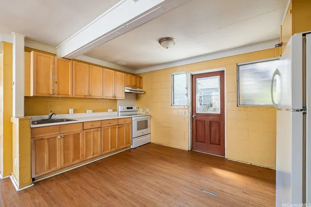 a kitchen with stainless steel appliances granite countertop a refrigerator a sink and white cabinets with wooden floor