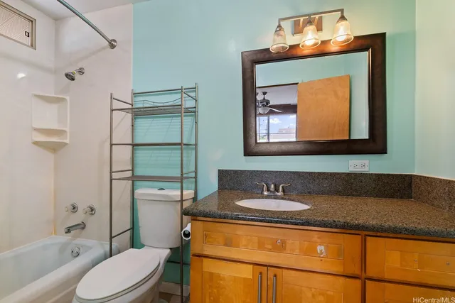 a bathroom with a granite countertop sink toilet and mirror