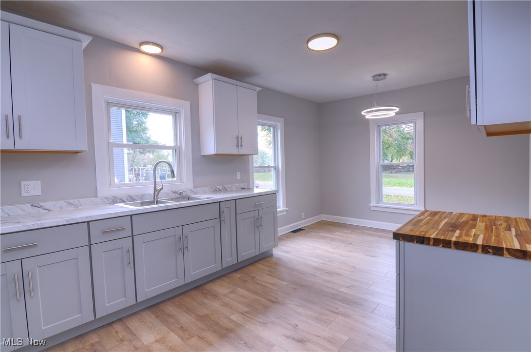 12341 Portage Street Rittman, OH 44270 - Photo 11 of 23 Kitchen with pendant lighting, sink, light hardwood / wood-style flooring, white cabinetry, and wood counters