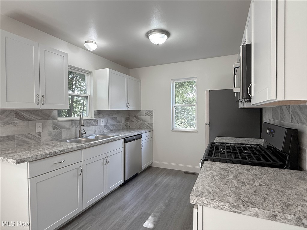 247 Reed Avenue Campbell, OH 44405 - Photo 8 of 41 Kitchen with backsplash, stainless steel appliances, white cabinetry, and light countertops