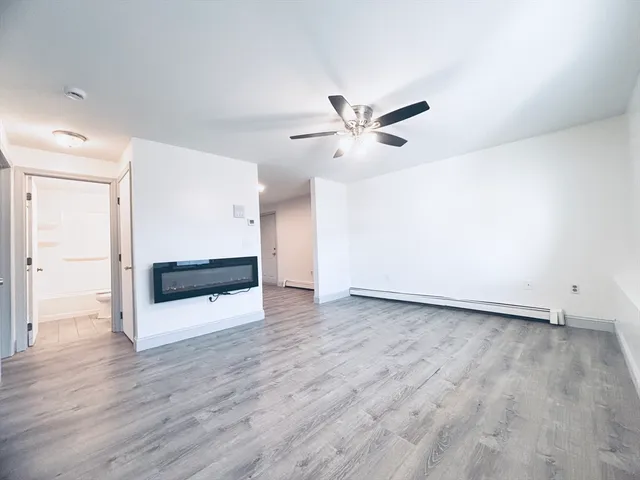 an empty room with wooden floor and ceiling fan
