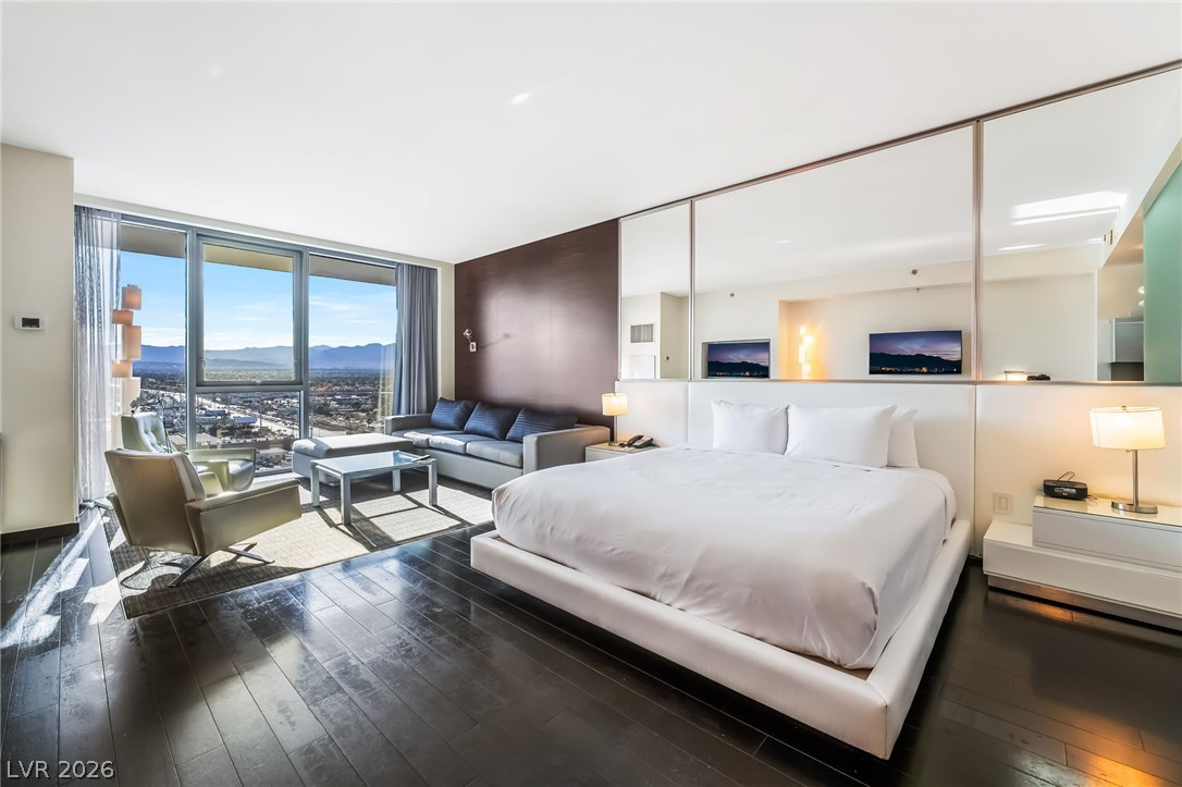 4381 West Flamingo Road, Unit 18305 Las Vegas, NV 89103 - Photo 11 of 19 Floor-to-ceiling windows offer captivating city views in this modern bedroom suite.