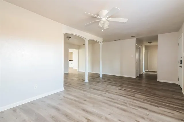an empty room with wooden floor and ceiling fan