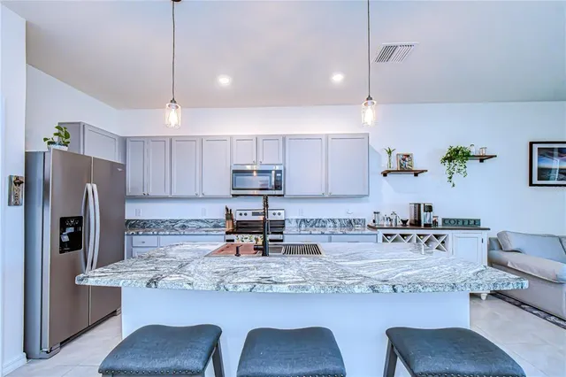 a kitchen with kitchen island granite countertop a stove a sink a refrigerator with a table and chairs