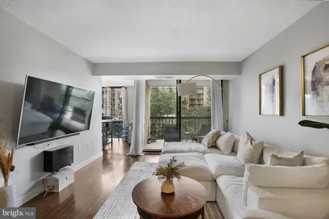 a living room with furniture a flat screen tv and a floor to ceiling window