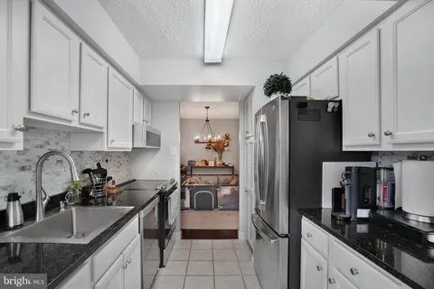a kitchen with granite countertop a refrigerator stove and sink