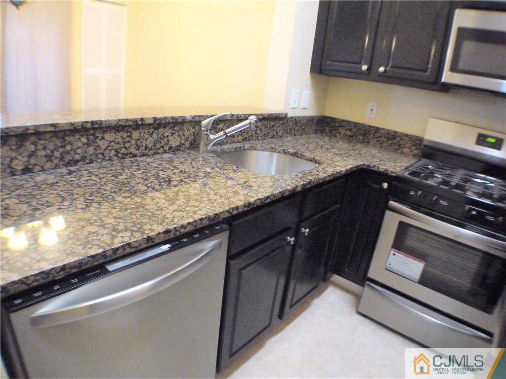 936 Edpas Road, Unit 936 New Brunswick, NJ 08901 - Photo 5 of 21 a kitchen with granite countertop a sink a stove and microwave