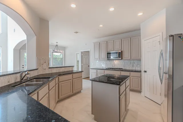 a kitchen with stainless steel appliances granite countertop a sink a stove and cabinets