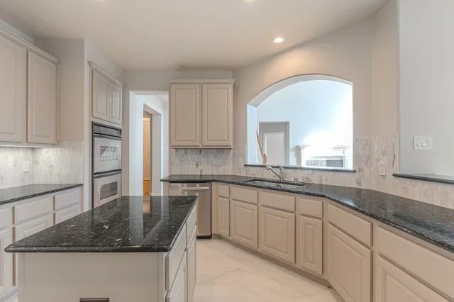 a kitchen with granite countertop a refrigerator and a sink