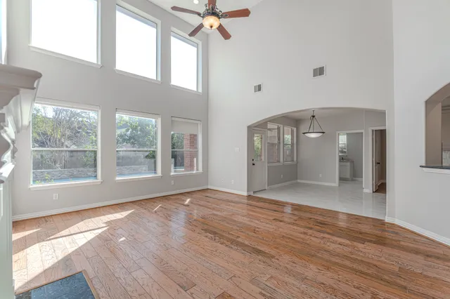 a view of an empty room with a window and wooden floor