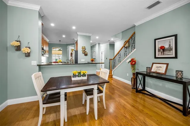 a kitchen with stainless steel appliances granite countertop a refrigerator a stove and a dining table with wooden floor