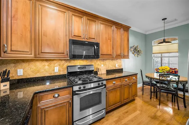 a kitchen with stainless steel appliances granite countertop a refrigerator a stove and a sink with cabinets