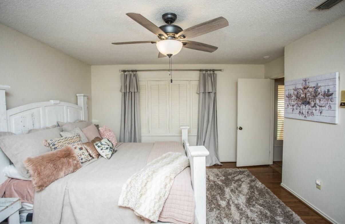 5202 20th Street Lubbock, TX 79407 - Photo 19 of 45 a bedroom with a large bed and a chandelier