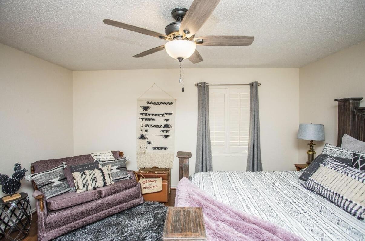 5202 20th Street Lubbock, TX 79407 - Photo 32 of 45 a bedroom with a bed couches and a chandelier
