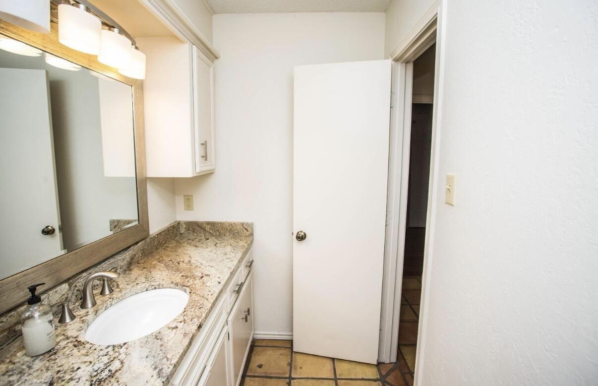 5202 20th Street Lubbock, TX 79407 - Photo 33 of 45 a bathroom with a granite countertop sink and a mirror