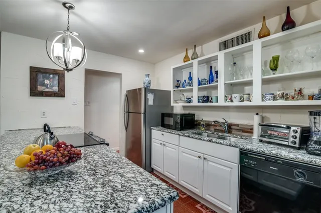 a kitchen with stainless steel appliances a chandelier a refrigerator and cabinets