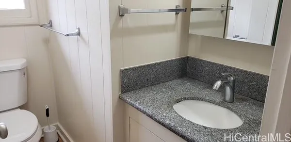 a bathroom with a granite countertop sink and a toilet