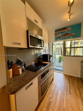 a kitchen with granite countertop a sink a stove top oven and cabinetry