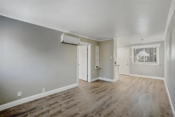 a view of an empty room with wooden floor and a window