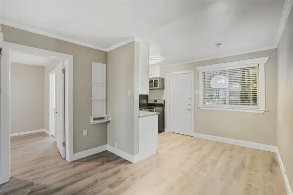 a view of an empty room with window and wooden floor