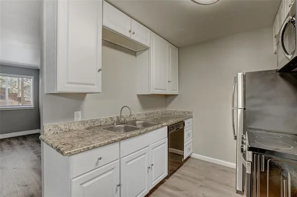 a kitchen with granite countertop a sink appliances and cabinets