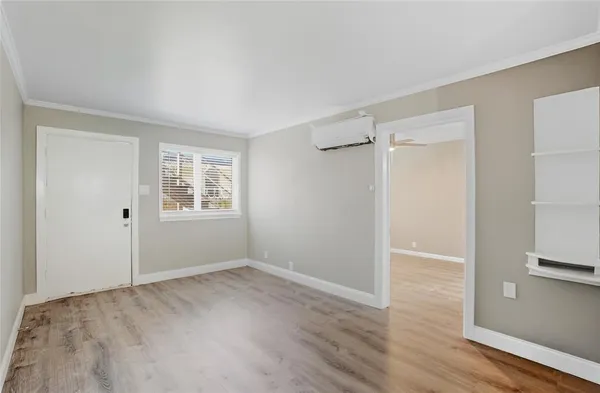 a view of an empty room with wooden floor and a window