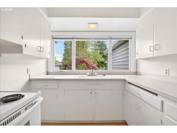 a kitchen with a sink a stove and white cabinets