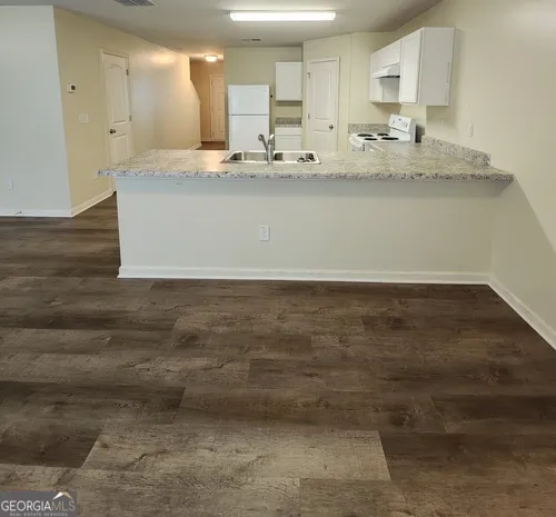 a view of kitchen with granite countertop cabinets and sink