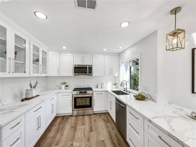 a kitchen with a sink stove cabinets and wooden floor