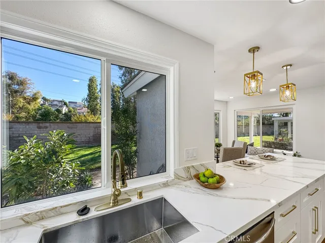 a view of kitchen island with granite countertop a sink and living room view